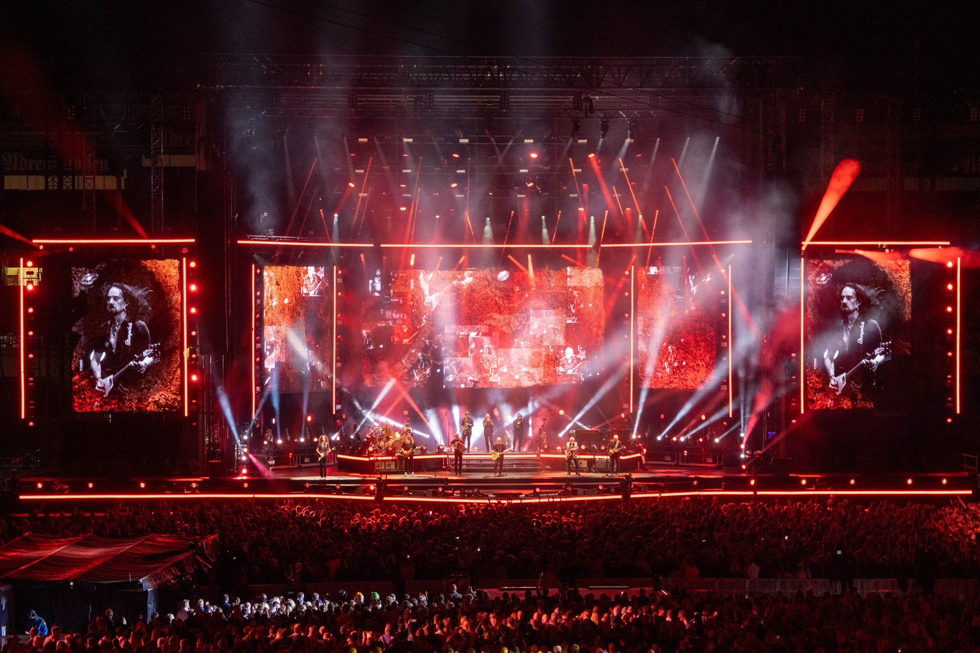 Åge Aleksandersen and Sambandet’s farewell concert at Lerkendal Stadium, with the stage, suspended speaker arrays and crowd under red and white lights.