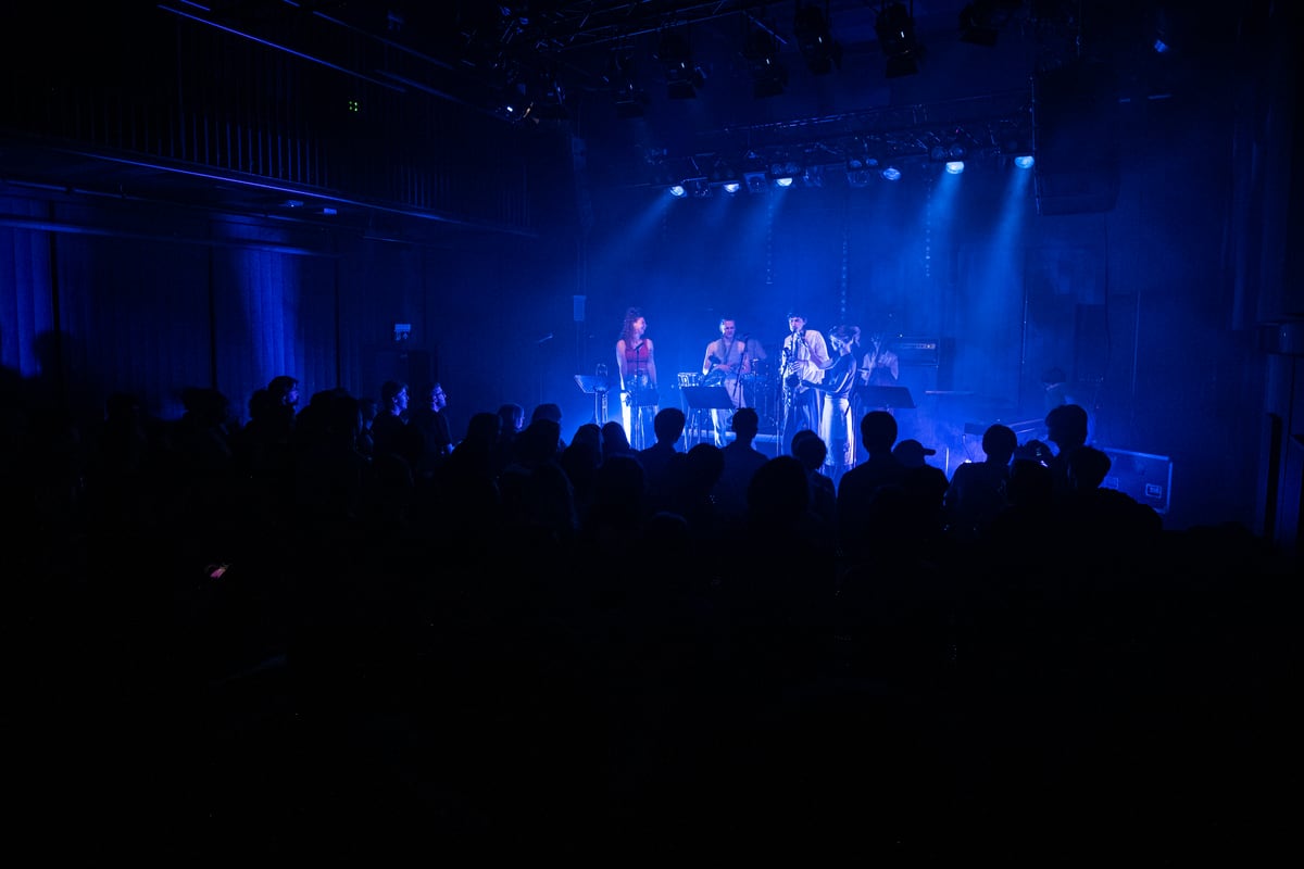 A blue-lit concert in Studentersamfundet’s Vuelie, with the stage, installed loudspeakers and audience in view.